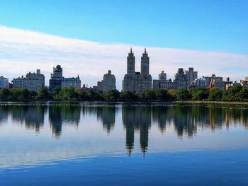 Reflection of buildings in lake against blue sky