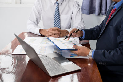 Midsection of doctor explaining to colleague in office