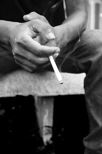 Midsection of man holding cigarette