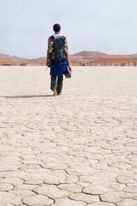 Rear view of woman walking on desert