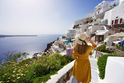 Rear view of woman standing by sea against sky