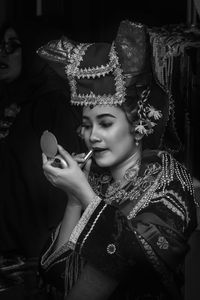 Close-up of woman in costume applying lipstick