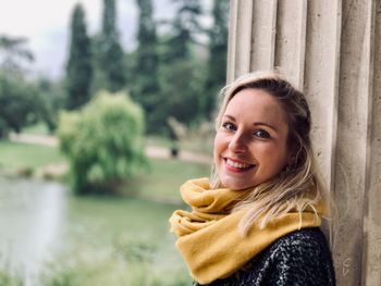 Portrait of smiling woman standing by tree