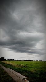 Scenic view of field against storm clouds