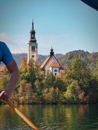 Low section of man standing by lake against sky