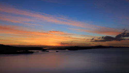 Scenic view of sea against cloudy sky during sunset