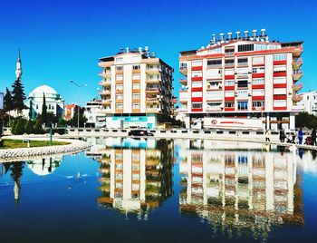 Reflection of buildings in lake against blue sky