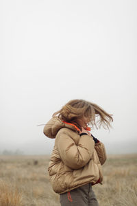 Rear view of woman standing on field against clear sky