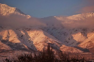 Majestic winter mountain at sunset surpassing clouds and shadowing a robin