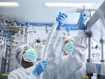 Chemical laboratory technicians fitting hose