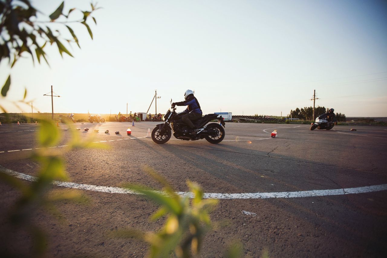 MAN RIDING MOTORCYCLE ON ROAD AGAINST SKY