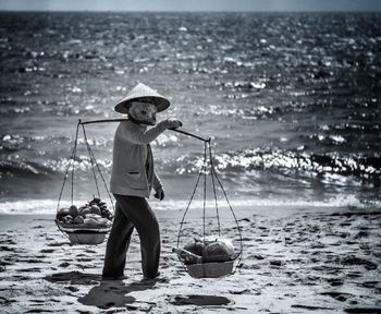 Man carrying vegetables in baskets at beach