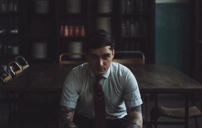 Portrait of young man sitting against table