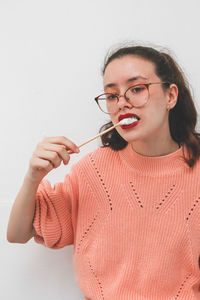 A teenage girl eats fried marshmallows on a skewer.