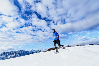 Rear view of man on snowcapped mountain against sky