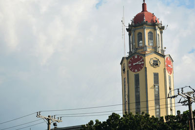 Low angle view of clock tower by building against sky