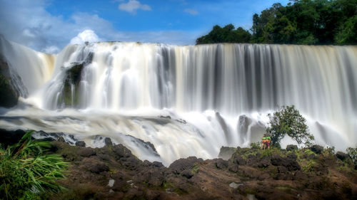 Scenic view of waterfall against sky