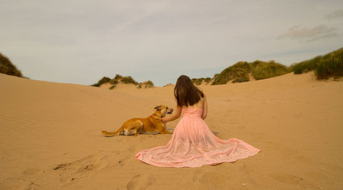 Woman with dog on beach against sky