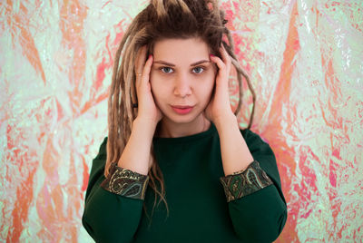 Portrait of beautiful young woman standing against wall