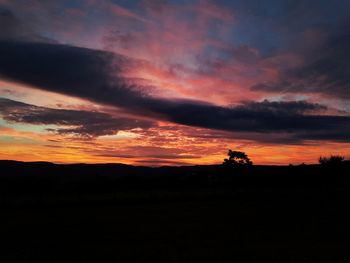 Scenic view of silhouette landscape against orange sky