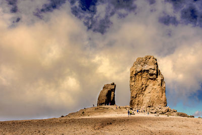 Statue on rock formation at desert against sky