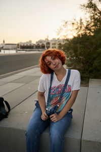 Young alternative redhead girl posing at sunset in a overall