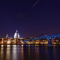 Illuminated london millennium footbridge over river in city at night