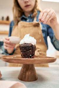 Midsection of woman holding ice cream on table