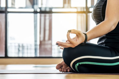 Midsection of woman sitting by window