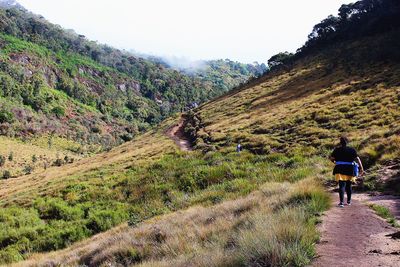 Rear view of people walking on mountain