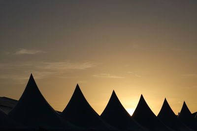 Silhouette built structures against sky during sunset