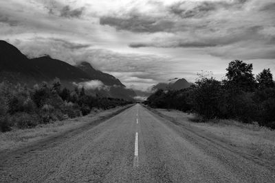 Road leading towards mountains against sky