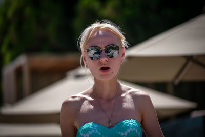 Portrait of shocked woman wearing sunglasses outdoors