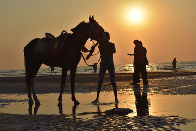 Silhouette of bonding between two friends and people walking on a beach