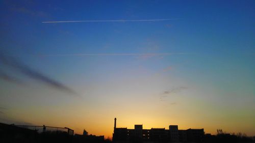 Low angle view of buildings against clear sky at sunset