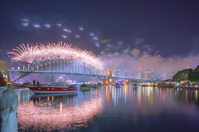 Firework display over river against sky