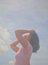 Woman with closed eyes standing against sky