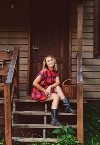 Portrait of a smiling young woman sitting on wood