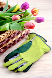 Close-up of tulips in basket with gardening gloves on table