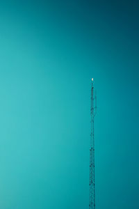 Low angle view of communications tower against clear blue sky