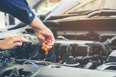 Cropped hands of mechanic repairing car in garage