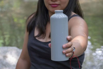 Midsection of woman holding water bottle