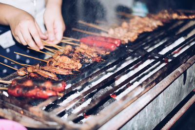 Close-up of man preparing food on barbecue grill