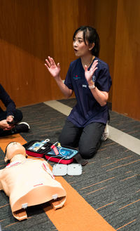 Full length of woman showing cpr over dummy on floor