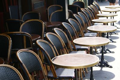 Empty chairs and tables at sidewalk cafe