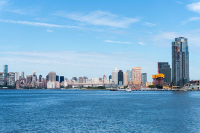 Sea by buildings against blue sky