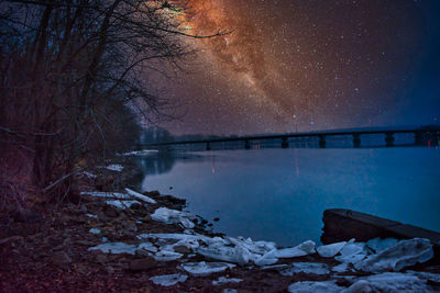 Scenic view of lake against sky at night during winter