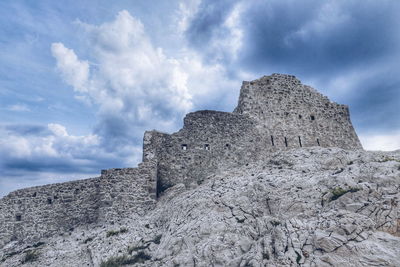 Low angle view of old building against cloudy sky