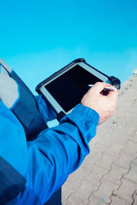 Midsection of man using digital tablet while standing on footpath