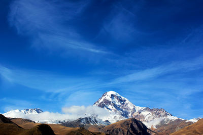 Scenic view of snowcapped mountains against blue sky